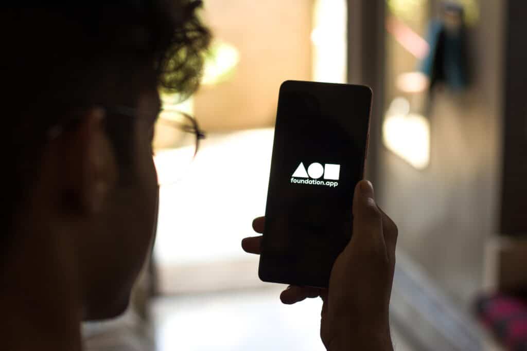 Holding Mobile with Foundation NFT Logo